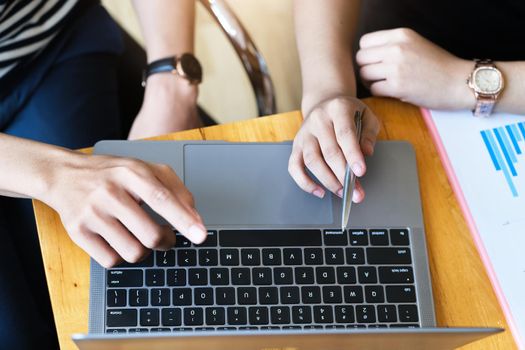 focus hand holding pen point to laptop screen with business woman and partnership discussion and exchange of ideas during work.