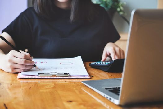 Business woman using document and using calculator to review balance sheet annual to calculating budget. for audit and Check integrity before investment.