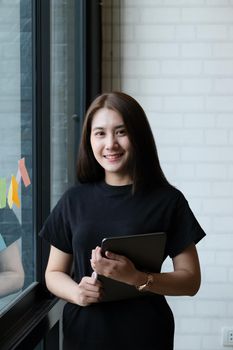 A female company employee uses a tablet and notepad to analyze company budgets