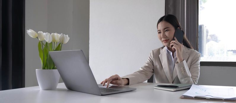 Young asian businesswoman beautiful charming smiling and talking on the mobile phone in the office..