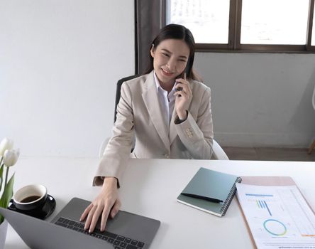 Young asian businesswoman beautiful charming smiling and talking on the mobile phone in the office..