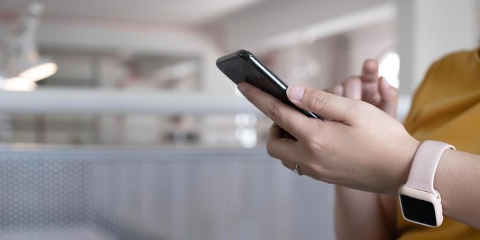 Close up hand of woman using smartphone at coffee shop cafe.