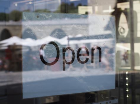 Open sign in a shop window with glass reflection