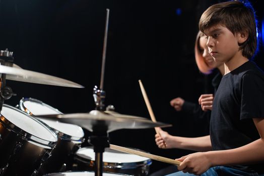 Young woman teaching boy to play drums