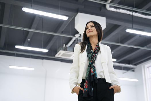 Confident caucasian professional woman achieving business success in modern office. Low angle shot.