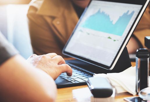 focus hands of a speculator who is using a tablet to trade stocks to make a profit on his own port