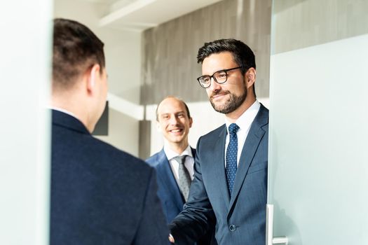 Group of confident business people greeting with a handshake at business meeting in modern office.