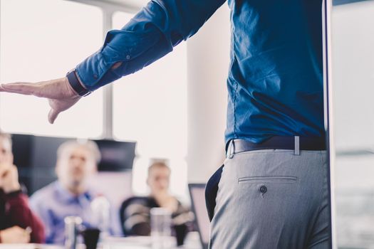 Business man making presentation at office. Executive delivering presentation to his colleagues during meeting or in-house business training, explaining business plans to his employees.