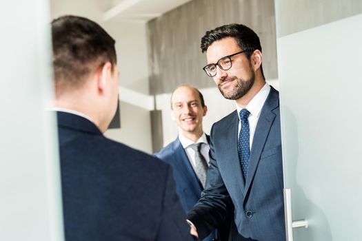 Group of confident business people greeting with a handshake at business meeting in modern office. Closing the deal agreement by shaking hands. Business and entrepreneurship success concept.