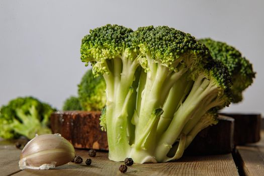 Raw green broccoli florets on a wooden board with ingredients. Close-up.
