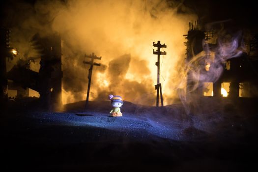 The death of children in the war. Russian war in Ukraine concept. Creative artwork of little doll lies on ground in burned out city. Selective focus