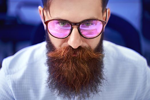 Senior developer working on computer in IT office, sitting at desk and coding, working on a project in software development company or startup. High quality image.