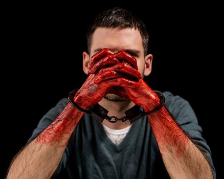 Portrait of a man with bloody hands handcuffed