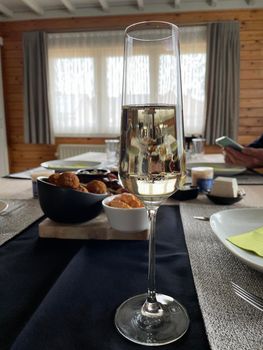 a glass of sparkling wine on the background of a set table with snacks, cheese plates and fruits for the holiday, table setting. High quality photo