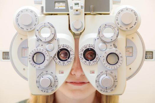 A male ophthalmologist checks a girl's eyesight using a phoropter. Vision treatment.
