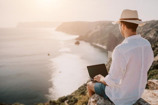 freelancer businessman working remotely on laptop at the beach near the sea