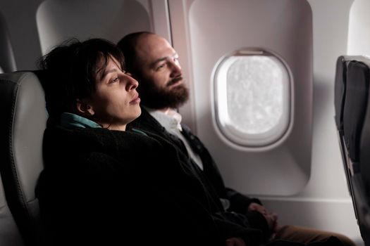 People tourists sitting in airplane waiting to takeoff, travelling abroad to go on holiday trip. Man and woman travellers using international airways on commercial flight, vacation destination.