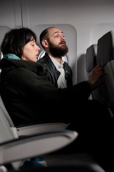 Man and woman travelling on vacation by airplane transport, waiting to takeoff on commercial flight in economy class, going to voyage destination. International airways on aerial transportation.
