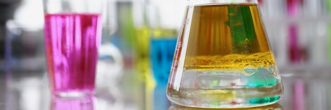 Close-up of glass flasks filled with different colours liquids for further investigation. Colourful research material on table. Science, lab, test concept