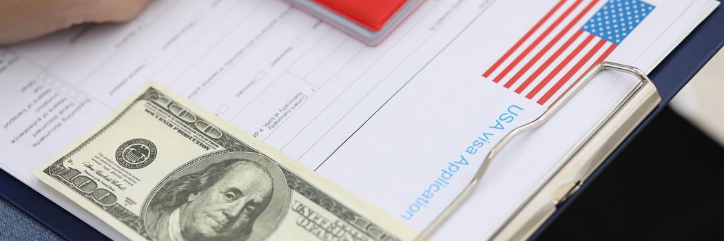 Close-up of visa application form paper with country national flag, passport and banknote. Empty line on list for personal information. Immigration concept