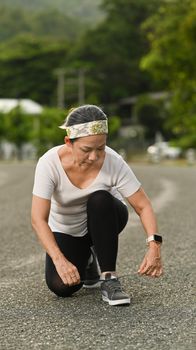 Middle aged woman tying shoelaces, getting ready for jogging in the morning. Sport and healthy lifestyle concept.