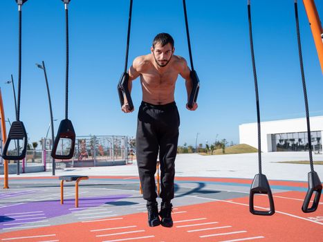 Shirtless man doing loop exercises outdoors