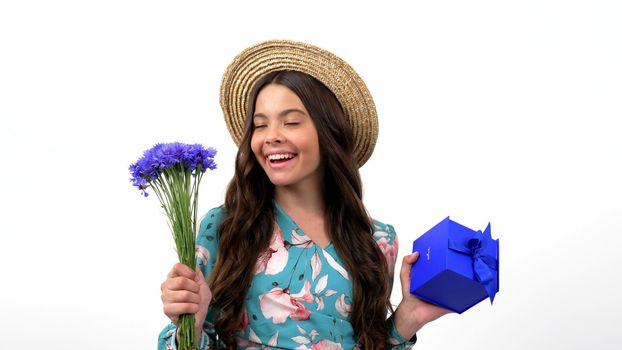 amazed happy child in summer straw hat turning with wildflower flower bouquet centaurea and present box, gift.