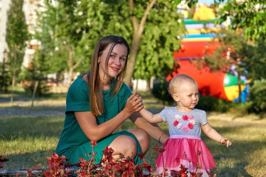 a girl or woman in relation to either or both of her parents.Cute mother with a charming baby daughter walks in the city park.