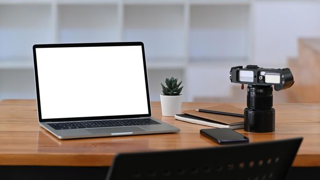 Computer laptop, camera and smart phone on wooden table.