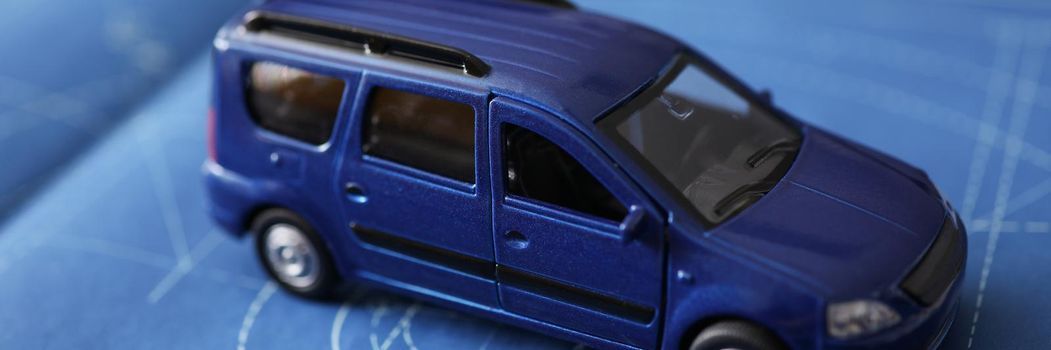 Close-up of new car model development, miniature automobile model on blueprint paper. Think about car insurance policy. Protection, safety, project concept