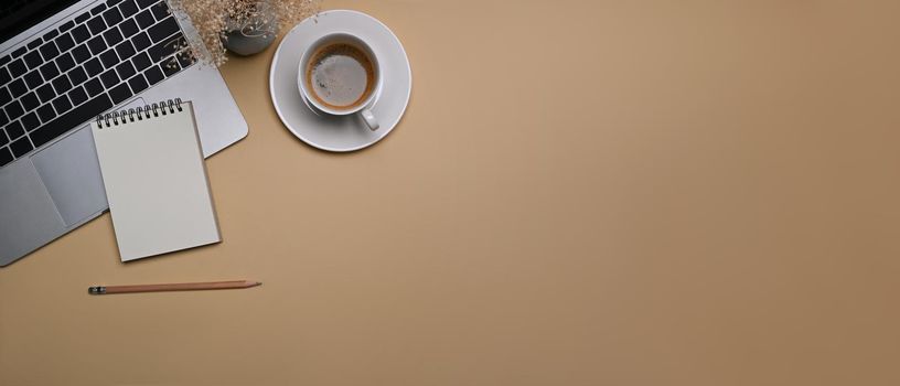 Laptop computer, coffee cup and notebook on beige background. Top view.