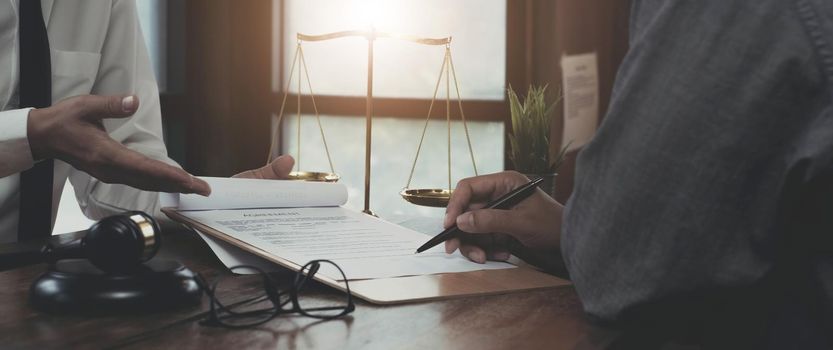 Businessman and lawyers discussing contract papers with brass scale on wooden desk in office. Law, legal services, advice, Justice concept..