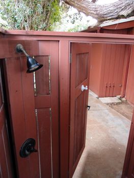 Red Walled Outdoor Shower with open door leading outside.