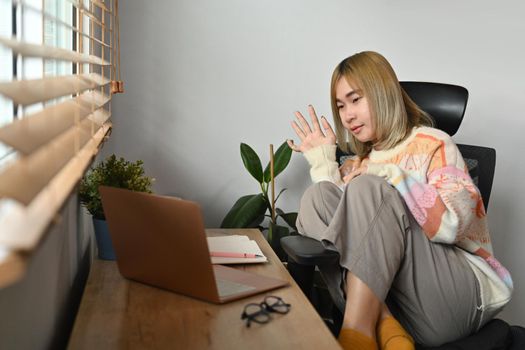 Young asian woman having video call on computer laptop in living room.