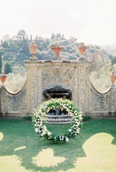 Wedding arch stands in front of a fountain in a stone wall with clay amphorae. High quality photo