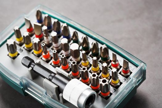 A set of metal power bits in a box on a gray background, for repair and maintenance