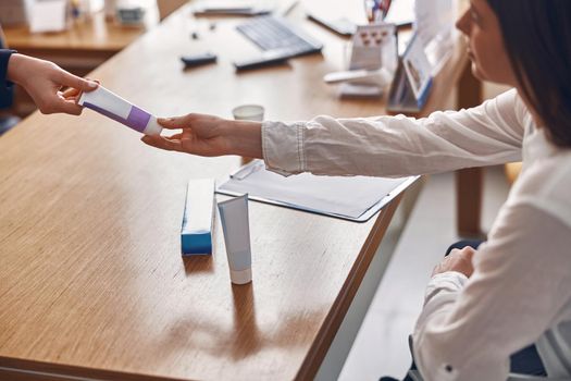 Happy woman is taking a toothpaste from hands of clinic personal