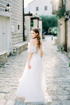 Bride stands half-turned on a cobbled narrow street of an old town. High quality photo
