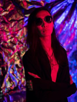 Portrait of a transgender model in sunglasses in a studio with neon lighting