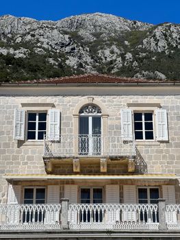 Stone facade of the building with openwork balconies against the backdrop of mountains. High quality photo