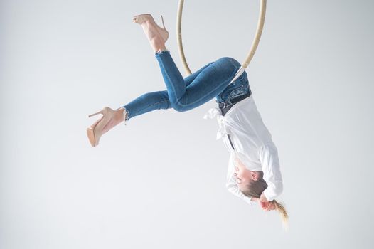 Caucasian woman in casual clothes on an aerial hoop