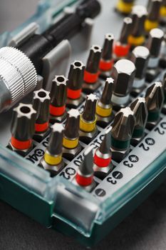 A set of metal power bits in a box on a gray background, for repair and maintenance