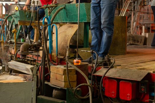 Beryozauka, Belarus - March 07, 2022: A team of glass blowers is working on the manufacture of glass vases and glasses. Up to 20 workers can be involved simultaneously in the production of particularly complex products.