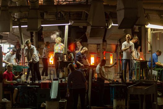 Beryozauka, Belarus - March 07, 2022: A team of glass blowers is working on the manufacture of glass vases and glasses. Up to 20 workers can be involved simultaneously in the production of particularly complex products.