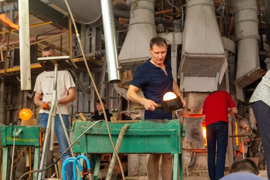 Beryozauka, Belarus - March 07, 2022: A team of glass blowers is working on the manufacture of glass vases and glasses. Up to 20 workers can be involved simultaneously in the production of particularly complex products.