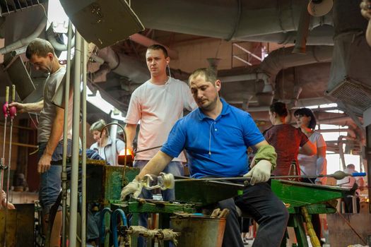 Beryozauka, Belarus - March 07, 2022: A team of glass blowers is working on the manufacture of glass vases and glasses. Up to 20 workers can be involved simultaneously in the production of particularly complex products.
