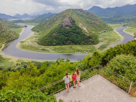 Tourists in the background Canyon of Rijeka Crnojevica river near the Skadar lake coast. One of the most famous views of Montenegro. River makes a turn between the mountains and flows backward.