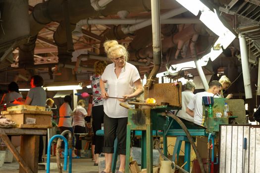 Beryozauka, Belarus - March 07, 2022: A team of glass blowers is working on the manufacture of glass vases and glasses. Up to 20 workers can be involved simultaneously in the production of particularly complex products.