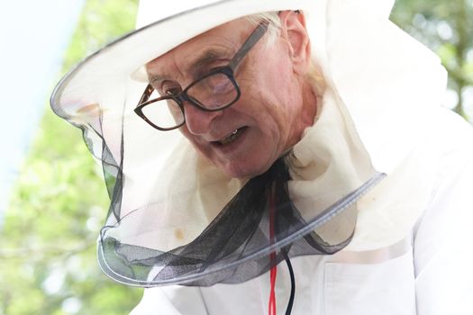 Low angle portrait of a concentrated beekeeper working with protective clothes