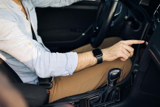 Unrecognizable man hand touching, clicking, tapping, sliding, dragging and swiping on screen monitor on modern luxury car. Interface concept.